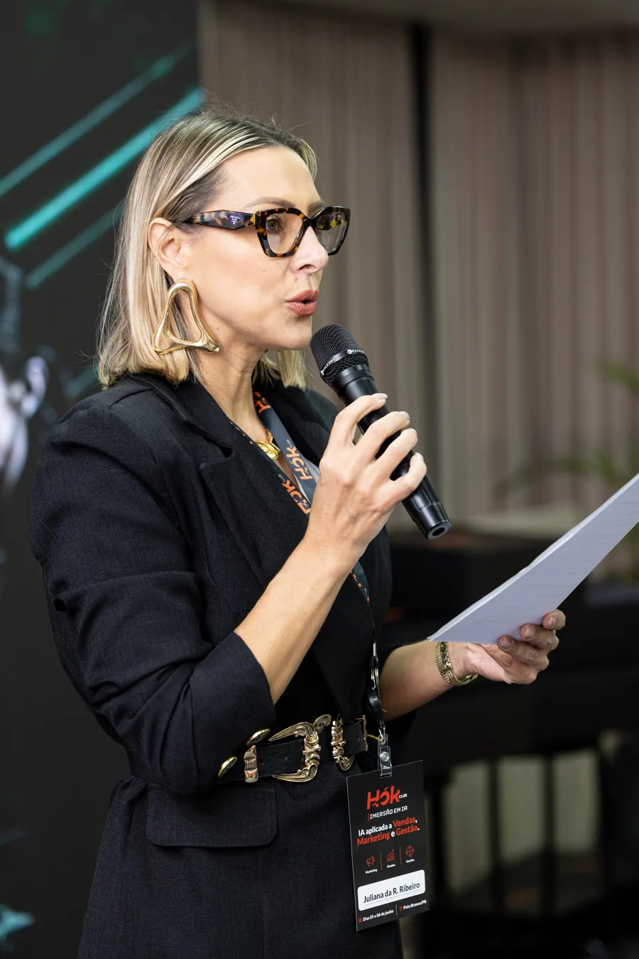Palestrante lendo anotações ao microfone no HOK Stage