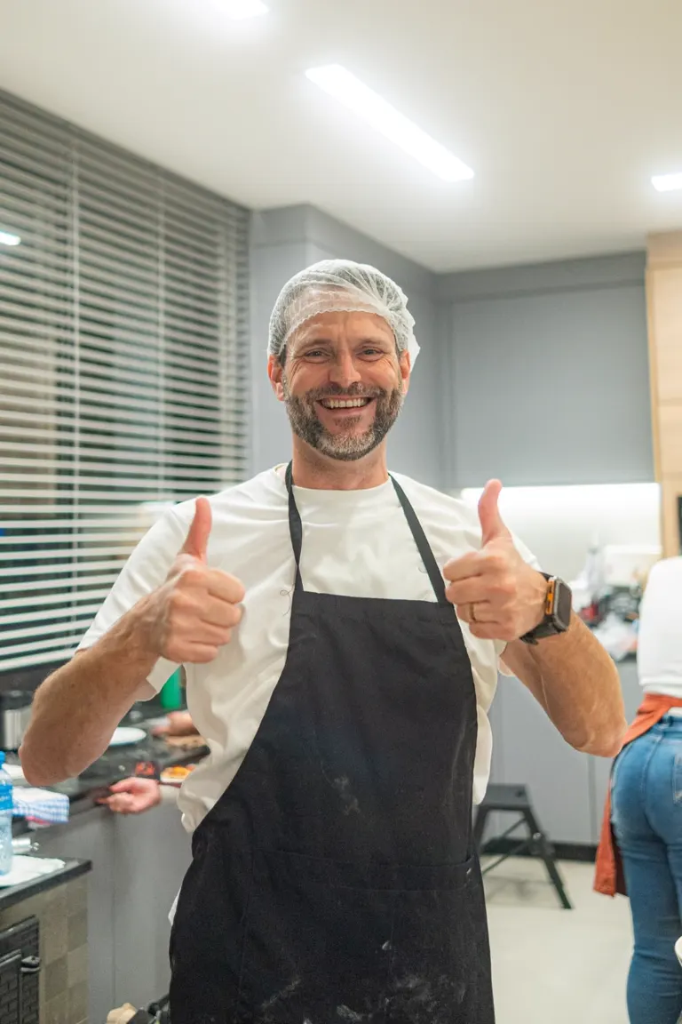 Participante de avental faz sinal positivo durante oficina de pizza do HOK