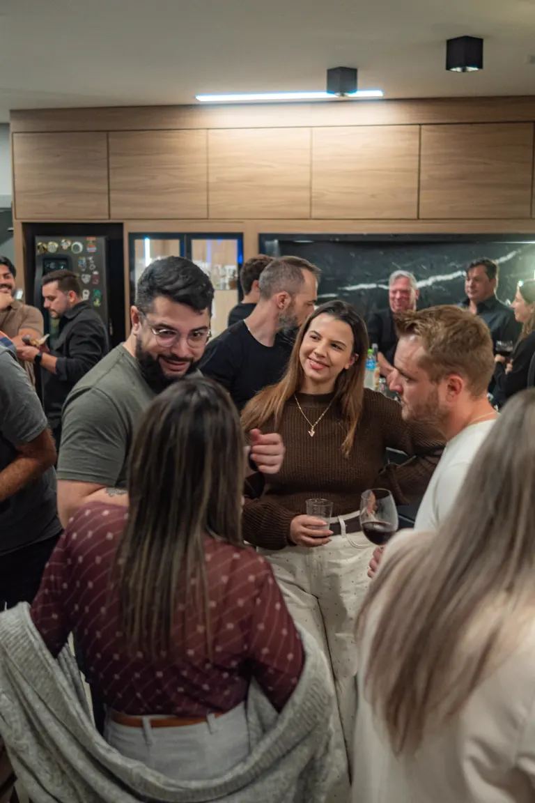 Grupo de participantes com bebidas em conversa durante encontro do HOK