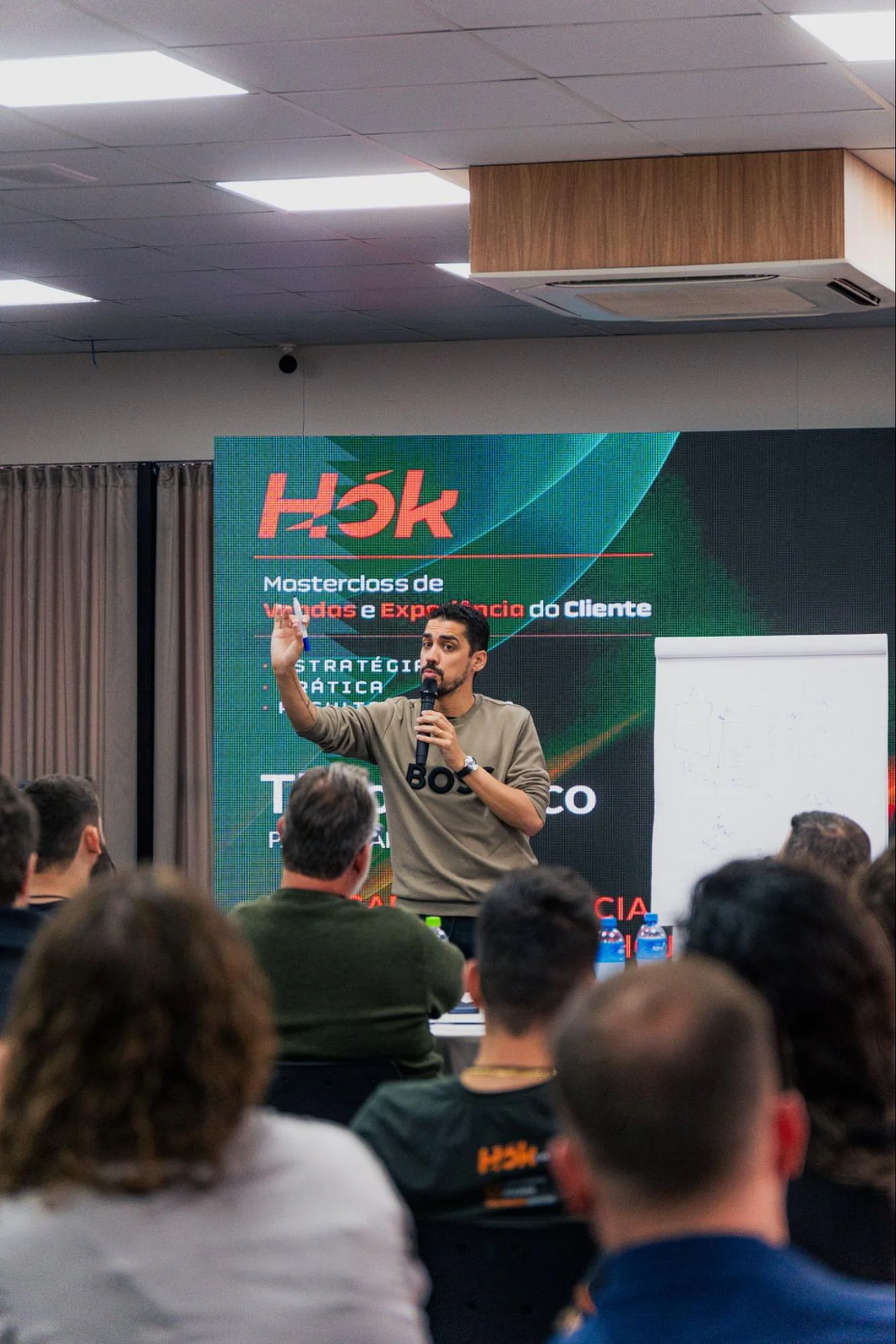 Palestrante com microfone em frente à plateia durante uma HOK Master Class